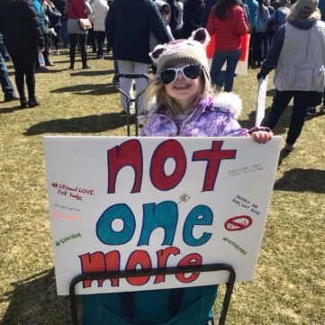 Rebekah Raz's youngest daughter poses with a sign at a rally